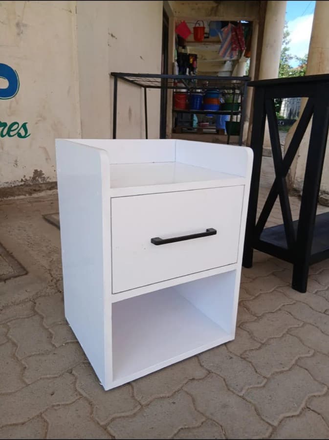 A finished bedside table standing on a workshop floor