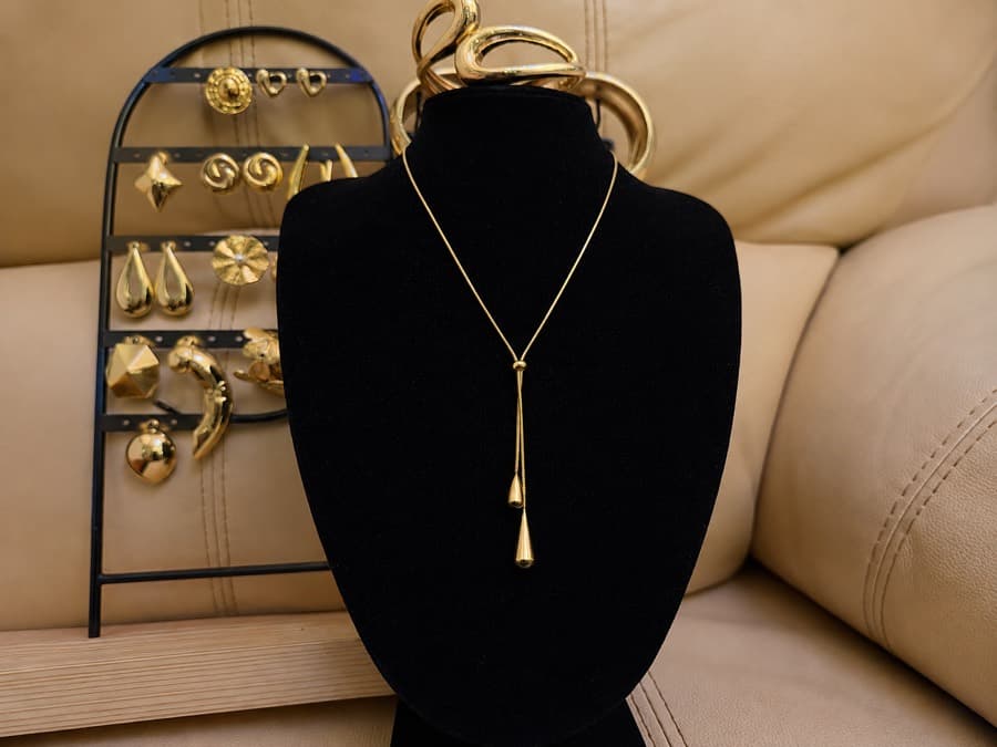 A gold pendant necklace on a display bust, the rest of the stock behind it